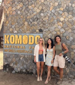 Tourists posing at the official Komodo National Park World Heritage Site entrance sign in Labuan Bajo